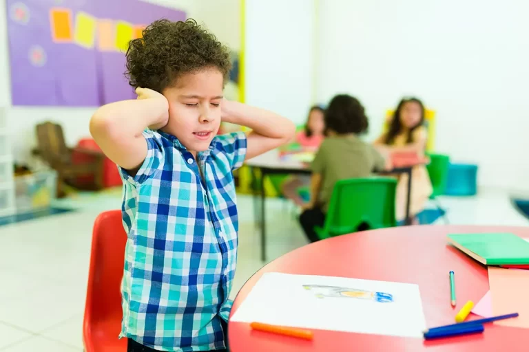 Young student holding ears in classroom